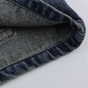 Dettaglio ravvicinato di cuciture rinforzate e orlo usurato su pantaloncini denim