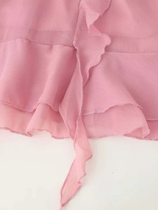 Dettaglio ravvicinato di balze a strati e lacci lunghi sull'abito estivo in chiffon rosa
