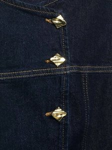 Detail of dark blue denim vest with three irregular gold diamond-shaped metal buttons