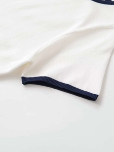 Close-up of white knit top showing navy contrast ribbed cuff and fine texture