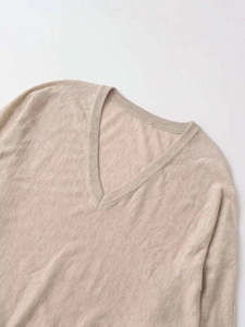Close-up of beige V-neck knitted sweater fabric texture and ribbed neckline detail