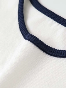 Close-up of contrast ribbed crew neck on white knit top with navy blue stitching detail