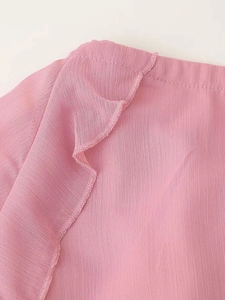 Dettaglio del tessuto in chiffon rosa con volant a strati e cuciture rifinite con cura