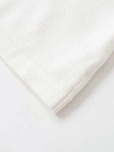 Close-up of premium white knit fabric showing fine texture and soft cotton material