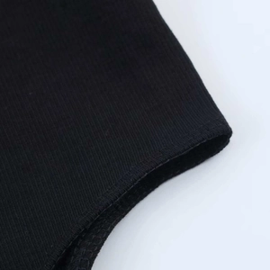 Detailed macro view of black ribbed knit fabric and reinforced stitched seam on edge