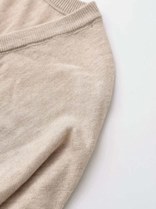 Detail view of beige V-neck sweater showing fine knit texture and ribbed neckline