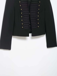 Dettaglio della giacca stile militare con bottoni dorati e finiture in treccia nera lucida