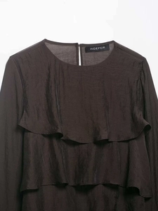 Detailed close-up of ruffled layered decoration and textured fabric on casual long-sleeve top