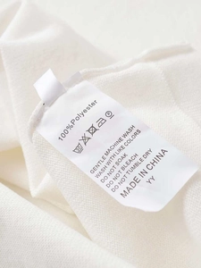 Close-up of white knit shirt care label showing 100% polyester fabric and washing instructions