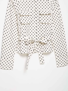 Détail du chemisier blanc à pois noirs avec poches poitrine et ceinture à nouer