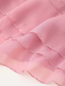 Dettaglio di un abito in chiffon rosa con balze a strati e texture a linee sottili
