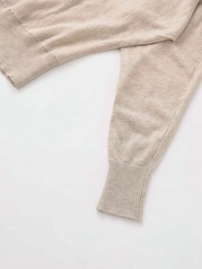 Detailed close-up of light beige knit fabric showing ribbed cuffs and high-quality texture