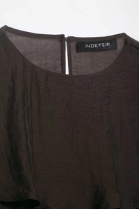 Detailed view of the dark asymmetrical top's back collar slit and refined fabric texture