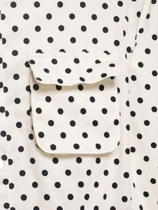 Détail d'un haut à pois blancs avec poche à rabat rectangulaire et couture nette