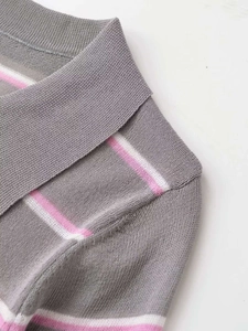 Dettaglio del colletto a polo in maglia grigia con strisce rosa e bianche su maglia