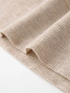 Close-up of beige ribbed knit fabric showing soft texture and fine vertical weave detail