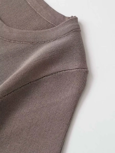 Detail of tan fine-knit texture and seamless crew neck stitching for summer sweater