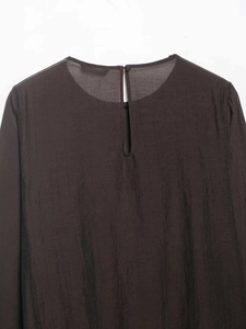 Detail of keyhole back closure and textured fabric on asymmetric pleated long sleeve top