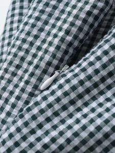 Détail de la fermeture éclair invisible sur le tissu vichy vert et blanc d'une robe