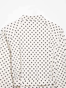 Détail du haut à pois blancs avec col montant et coupe de manches raglan précise