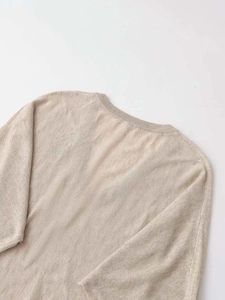 Detailed view of the soft beige knitted texture and ribbed neckline of the V-neck sweater