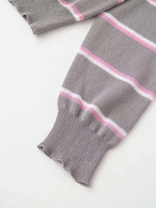 Dettaglio della manica in maglia grigia con strisce rosa e bianche e polsini a coste