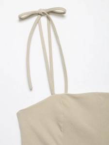 Detailed close-up of light beige camisole top featuring delicate bow-tie shoulder straps