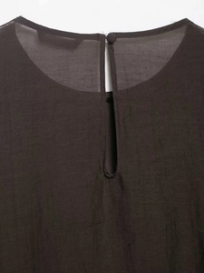 Detail of keyhole back with button closure on minimalist dark brown layered top