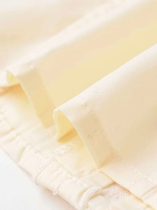 Detailed macro view showing the clean rolled hem stitching on this beige cotton shirt