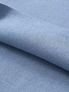 Macro shot of light blue knitted fabric detail with fine texture and neat stitching