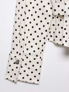 Détail des poignets larges et de la ceinture sur le chemisier à pois à manches longues