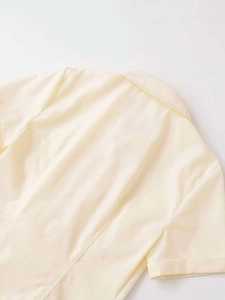 Detail of short sleeve shirt back seam and folded cuffs in light cream woven fabric