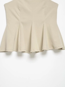 Detailed view of the pleated skirt hem with vertical ruffles in a light beige fabric