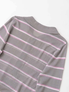 Dettaglio del colletto polo e trama a righe rosa sul maglione grigio a maniche lunghe