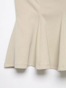 Detailed close-up of beige camisole peplum hem with double-stitch sewing craft