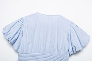 Close-up of light blue shirt with puff sleeves and detailed horizontal waist pleats