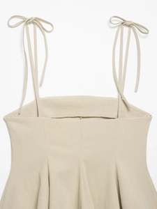 Detail view of adjustable bow shoulder straps and textured beige fabric on a summer top