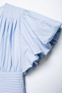Detail of light blue shirt featuring pleated bodice and ruffled puff sleeves texture