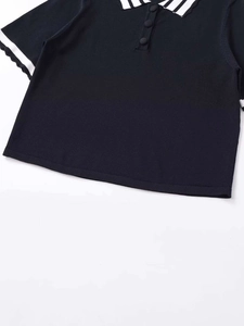 Close-up of black knit polo shirt with contrast scalloped collar and button details