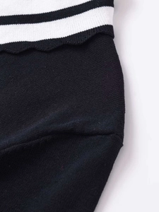 Detail of black knit fabric with white striped scalloped edge and fine texture