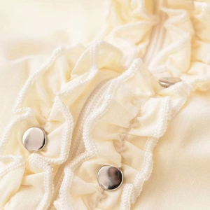 Cream ruffed sleeveless shirt for women featuring delicate layered ruffles and silver snap buttons