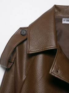 Close-up of brown leather jacket shoulder with epaulet detail and grained texture