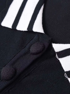 Detail of black knit top featuring a striped collar and matching fabric-covered buttons