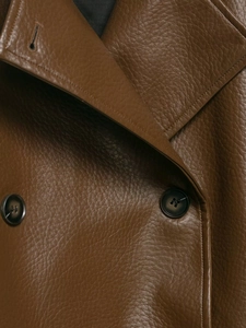 Close-up of brown faux leather jacket texture featuring lapels and resin buttons