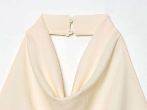 Dettaglio della chiusura a girocollo con due bottoni su un gilet in crêpe beige