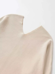 Detail of V-neckline on a beige knit sweater featuring fine knitting texture and soft fabric