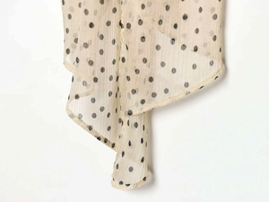 Detail of light beige polka dot chiffon fabric with fine pleated texture and hem finish