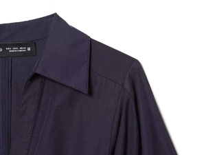 Détail du col d'une robe bleu marine avec étiquette de taille et coutures précises
