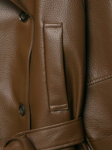 Detail shot of brown faux leather jacket texture with buttons and waist belt design