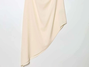 Dettaglio del top beige a lupetto con orlo asimmetrico e trama in tessuto crepe